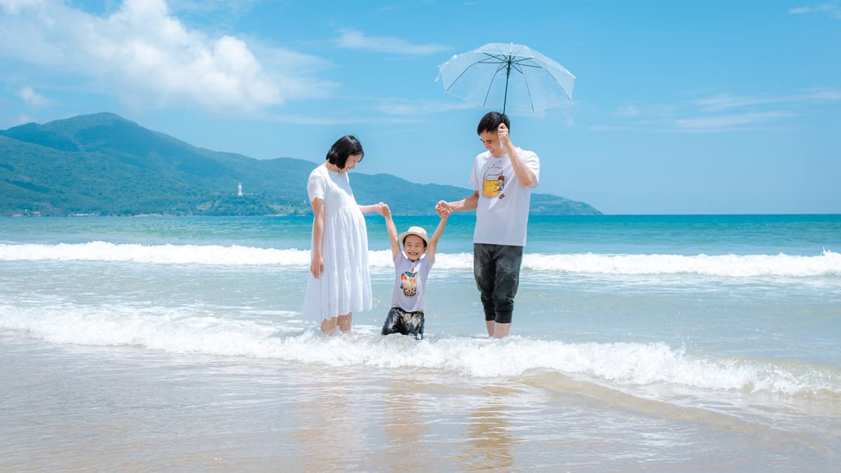 Happy family enjoying a sunny day at Da Nang Beach, Vietnam, playing in the waves.